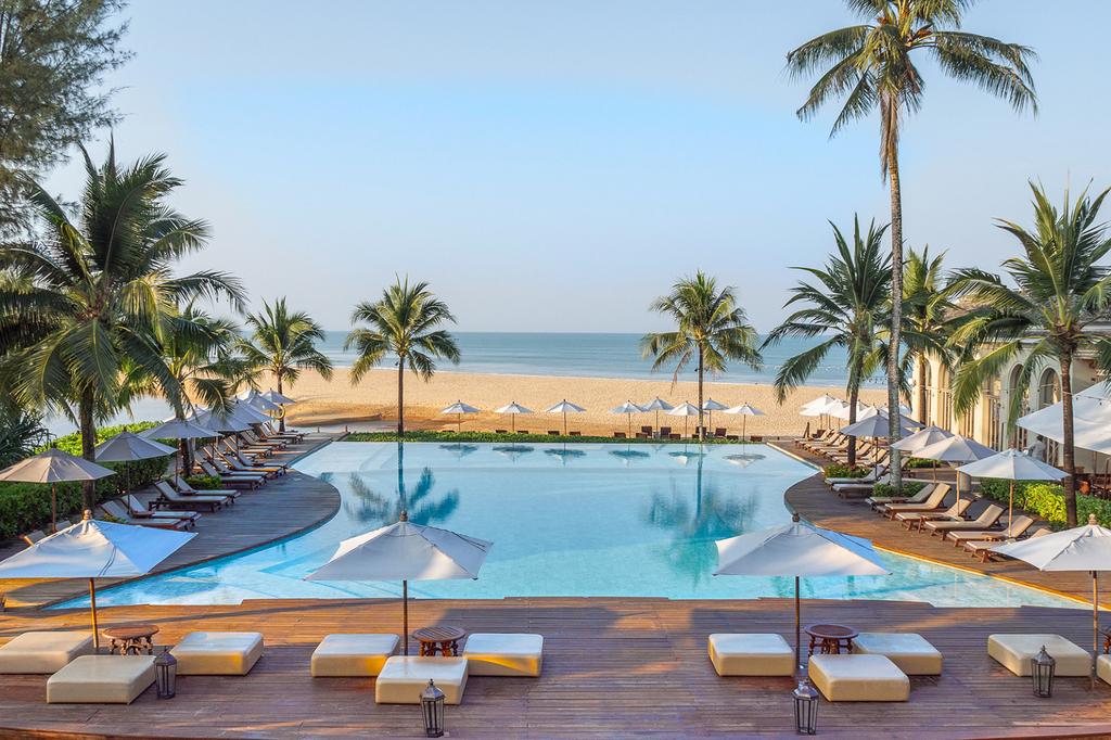 Beachfront pool at Devasom Khao Lak Beach Resort with pristine shoreline.