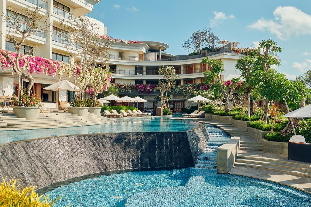 Luxurious pool with sun loungers and lush greenery at at AYANA Segara Bali.