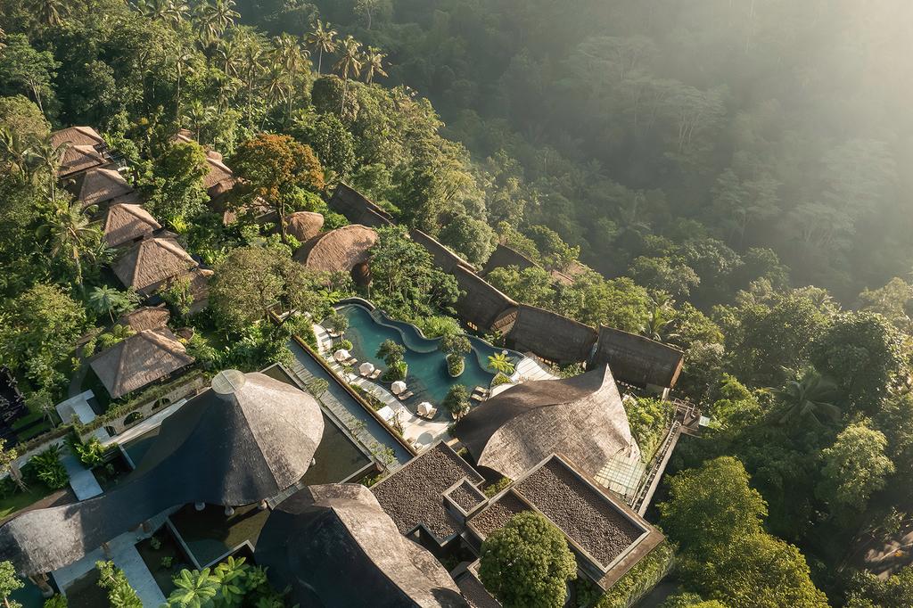 Aerial view of luxurious pool villas surrounded by lush jungle in Bali. 