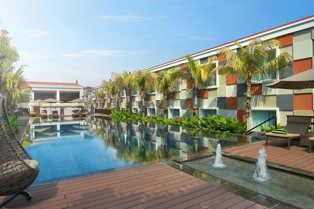 Outdoor pool area at a tropical hotel in Bali with sun loungers.
