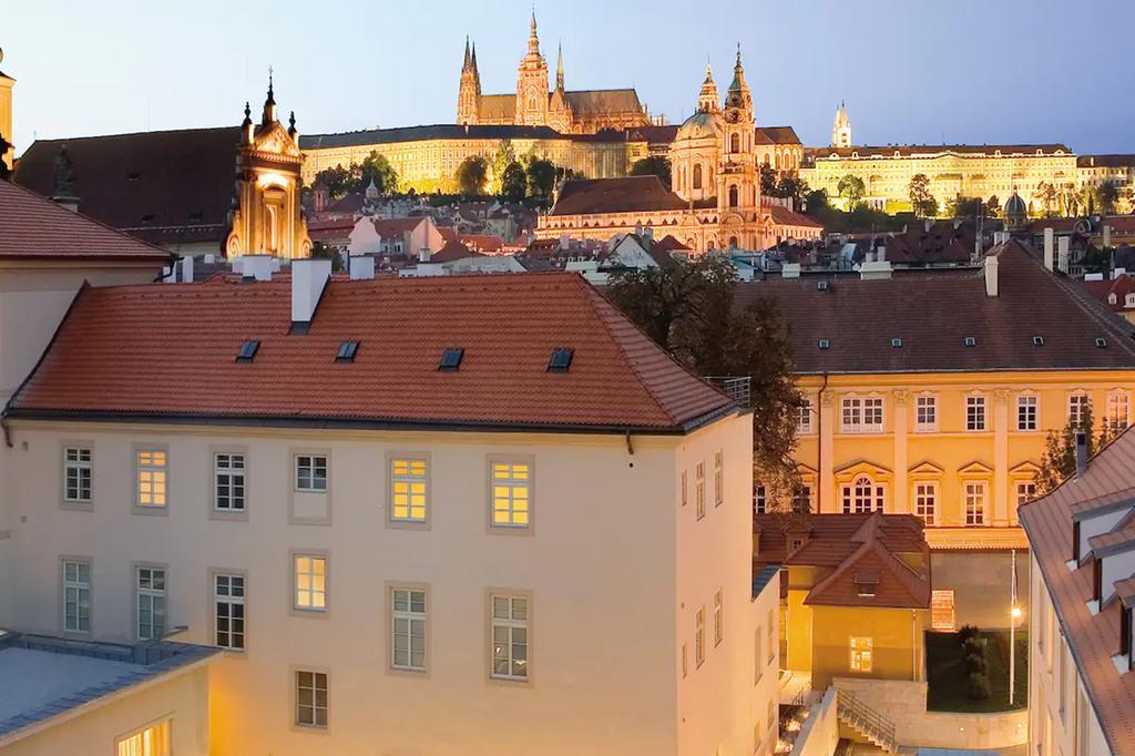 View of Prague Castle from a historic hotel terrace at dusk.