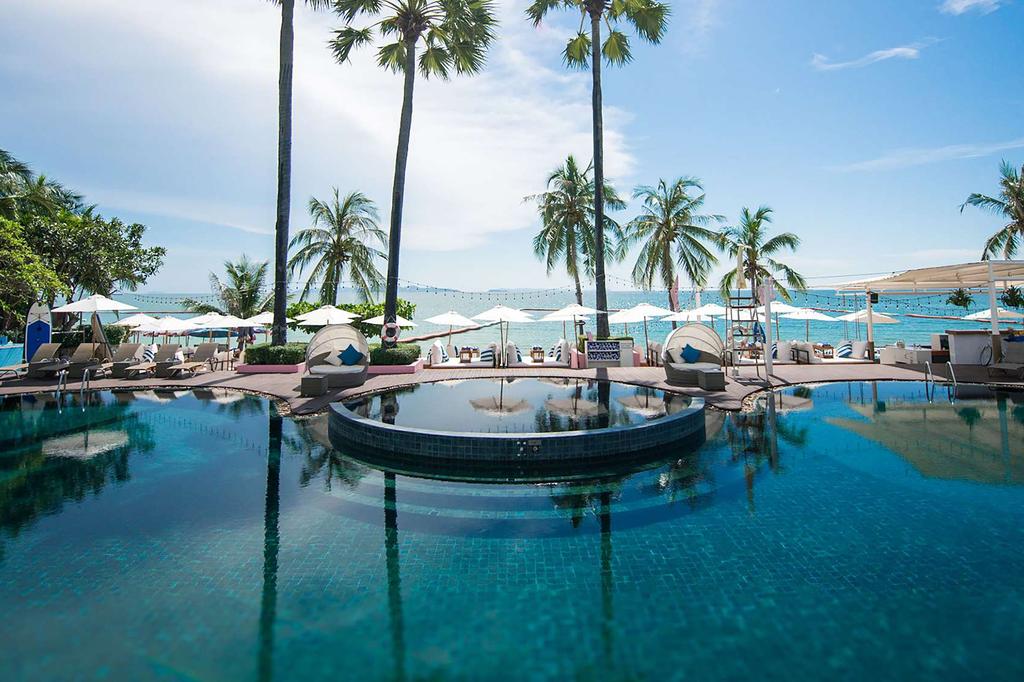Luxury resort pool with ocean view and palm trees in Pattaya.