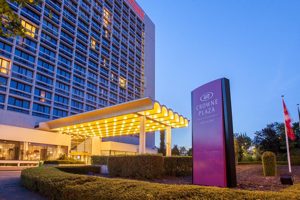 Crowne Plaza Antwerp entrance illuminated at dusk.