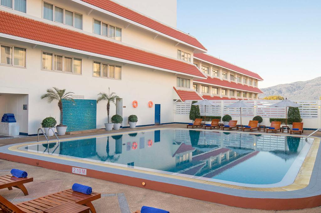 Chiang Mai hotel pool area with sun loungers and scenic views.