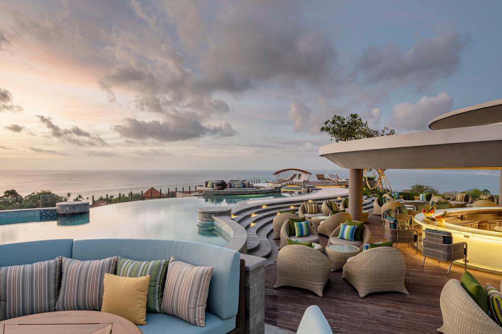 Rooftop infinity pool and lounge area overlooking the ocean at sunset. 