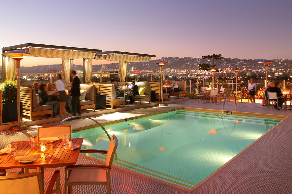 Rooftop pool and bar at night with views of the city skyline.