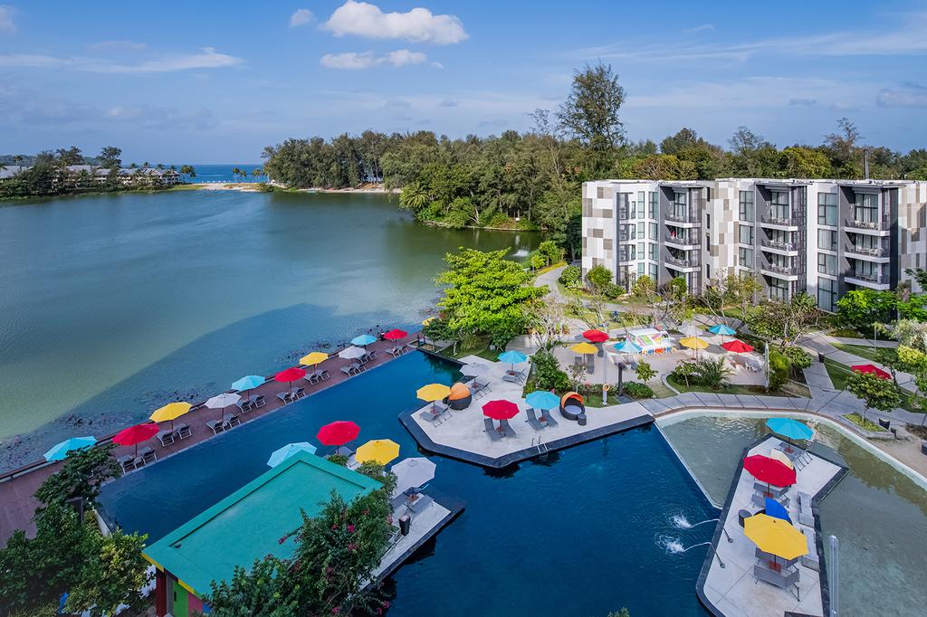 Aerial view of Cassia Phuket resort by a serene bay.