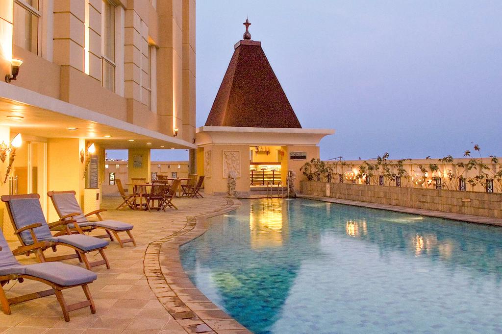 Elegant outdoor pool at Novotel Semarang with seating area.