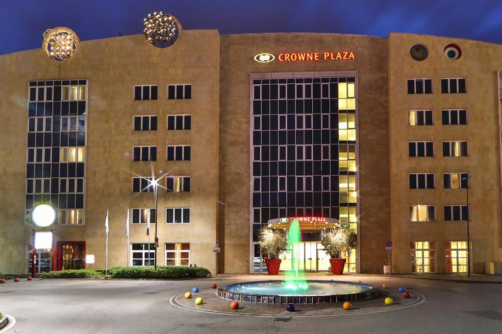 Elegant facade of Crowne Plaza Padova at night with lit fountain.