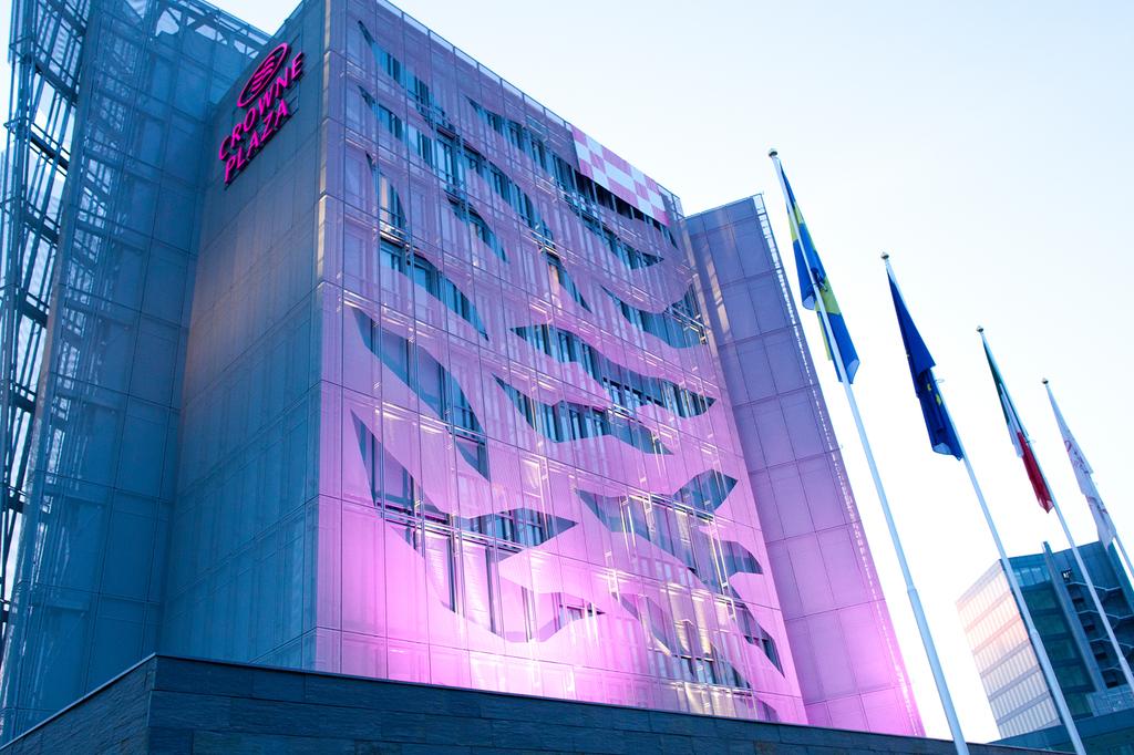 Crowne Plaza Verona illuminated exterior with flags displayed.
