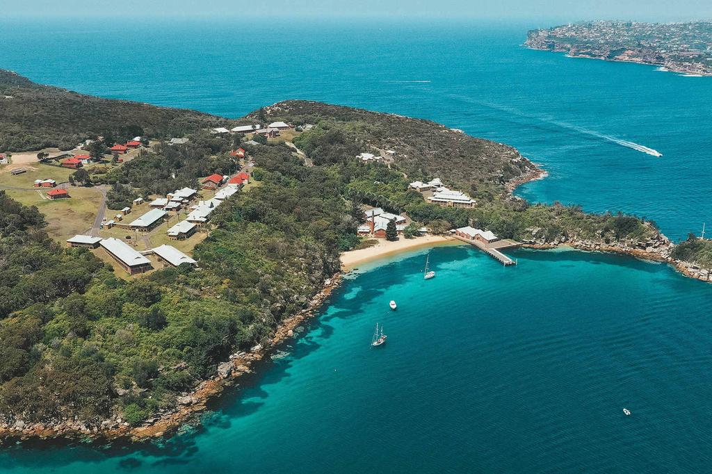 Aerial view of secluded beachfront and historical cottages near Sydney Harbour.