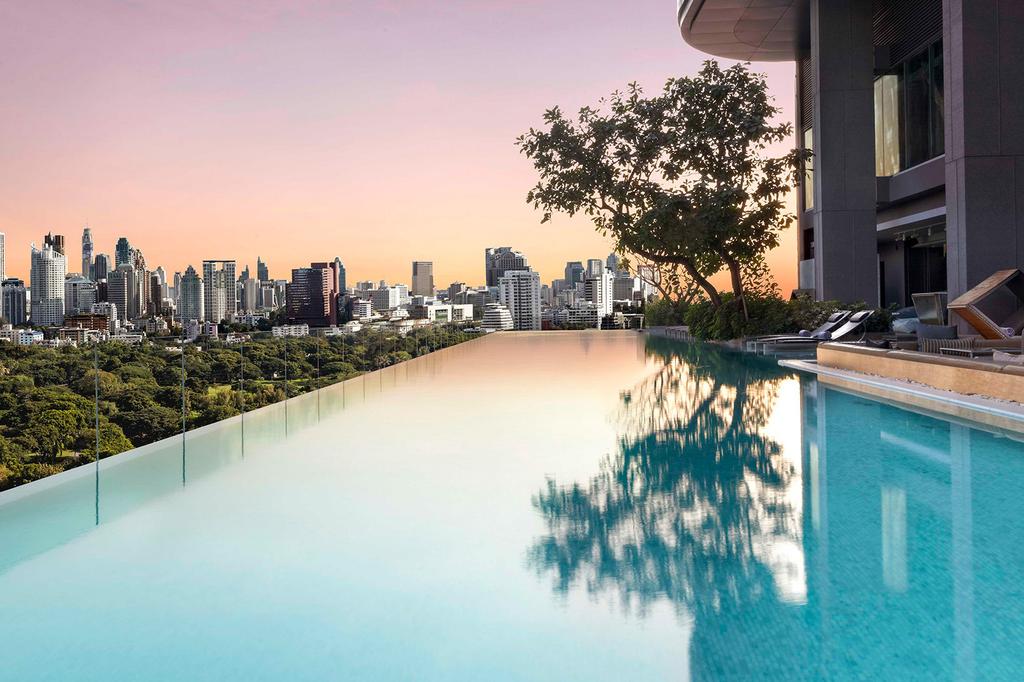 Rooftop infinity pool overlooking Bangkok and Lumphini Park at sunset.