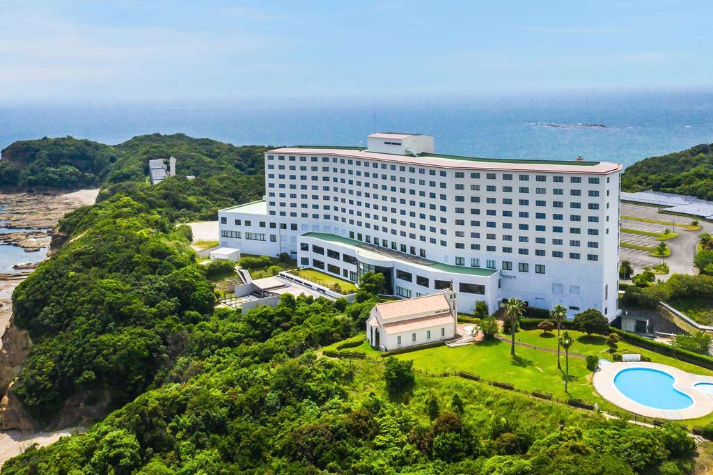 Oceanfront Japanese hotel surrounded by lush greenery and coastal views.