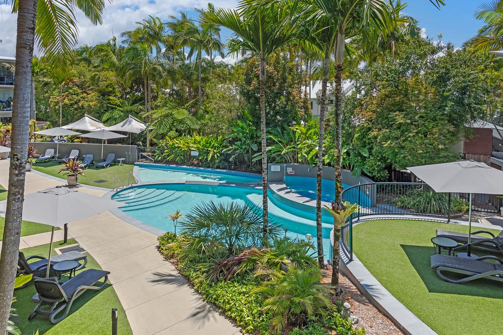 Outdoor pool surrounded by lush gardens at a Noosaville apartment resort.