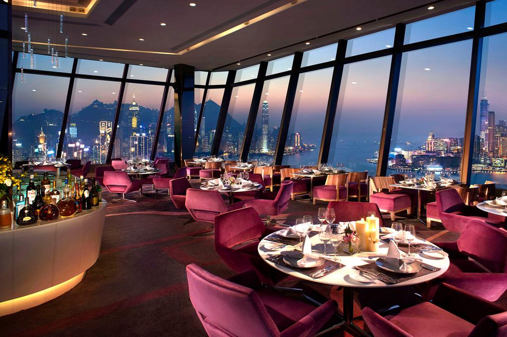 Luxurious dining area with panoramic views of Hong Kong skyline at sunset.