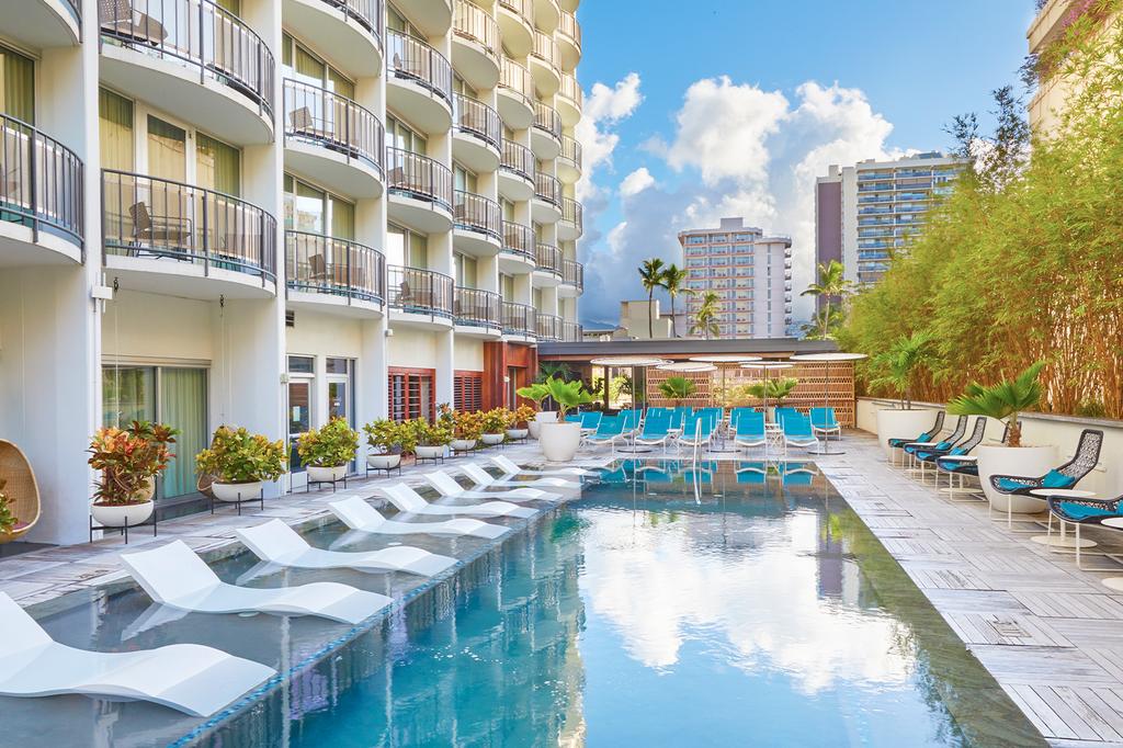 Luxurious The Laylow Waikiki, Autograph Collection pool surrounded by tropical greenery.