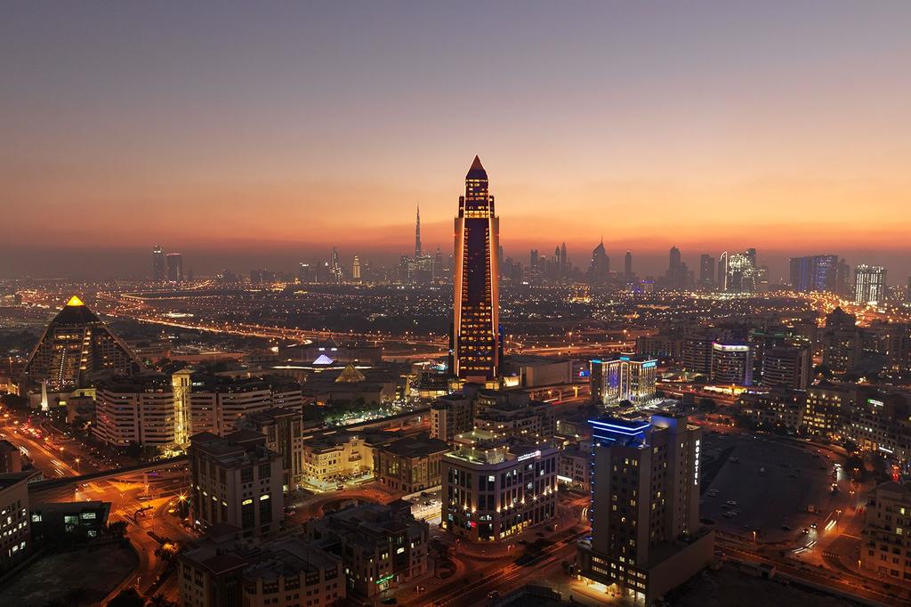 Dubai skyline at sunset with prominent skyscrapers and city lights.