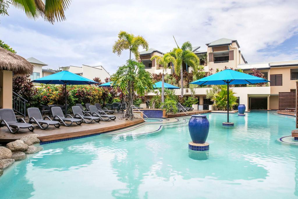 Lagoon-style pool at a lush Port Douglas resort with sun loungers and umbrellas.