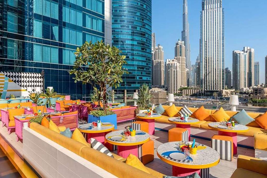 Rooftop pool lounge with colorful seating and Burj Khalifa view in Dubai.
