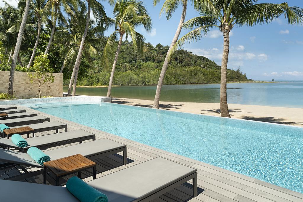 Infinity pool at Avani+ Samui Resort beachfront with palm trees and ocean view.