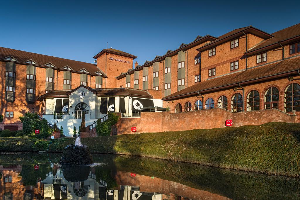 Crowne Plaza Solihull with gardens and lake view under a clear sky.