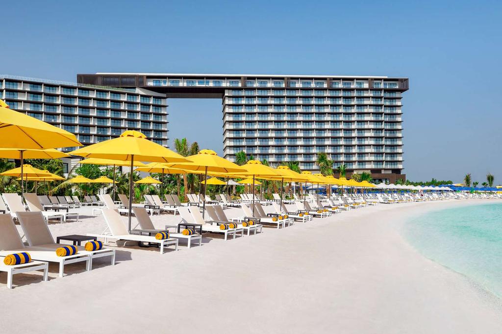 Beachfront resort on Al Marjan Island with sun loungers and umbrellas.