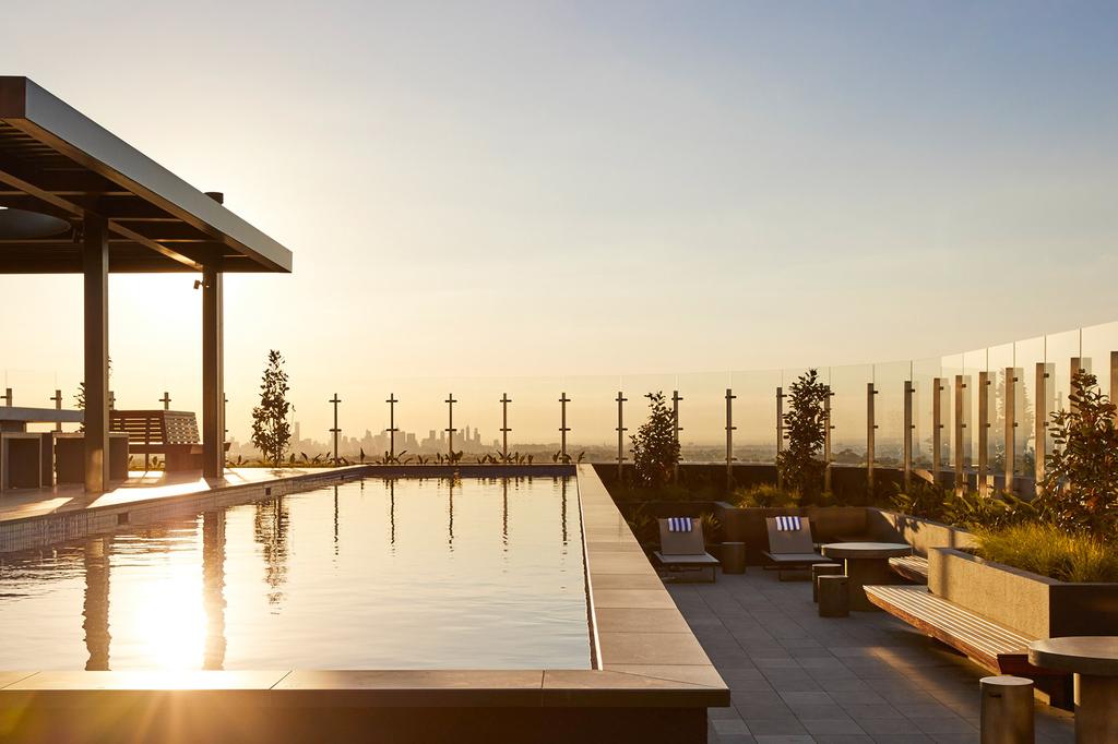 Rooftop pool with views of Melbourne skyline at sunset.
