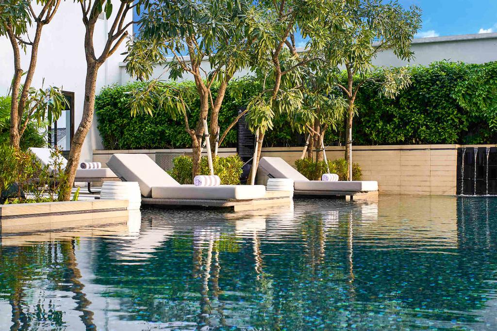 Luxurious rooftop pool at Pullman Bandung with modern sun loungers and greenery.