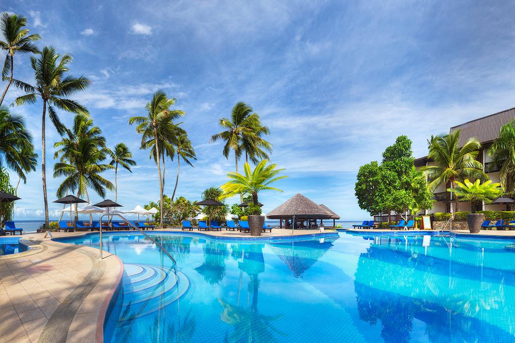 Luxurious resort pool surrounded by palm trees on Fiji's Coral Coast. 