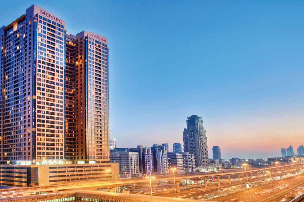 Modern hotel towering over Dubai's dynamic skyline at sunset.