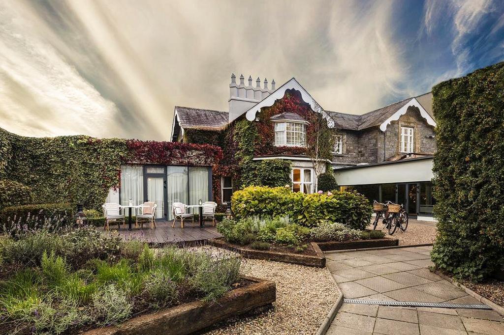 Charming hotel exterior with lush gardens and outdoor seating.