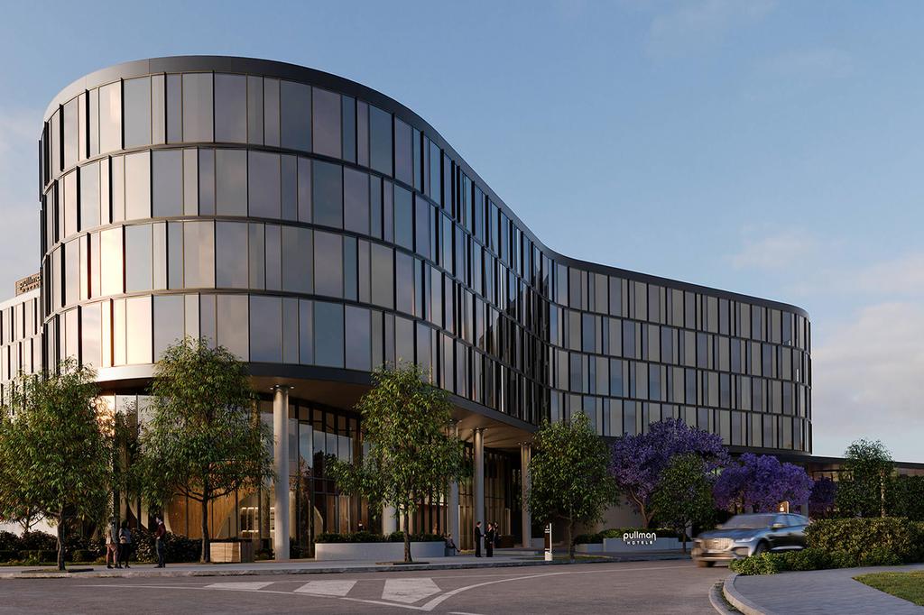 Modern facade of Pullman Sydney Penrith hotel with trees in foreground.