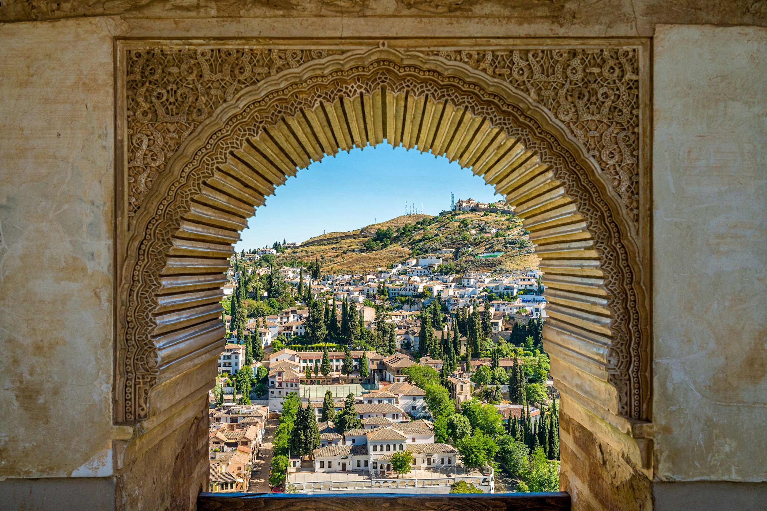 View of Albaicín district through ornate Moorish arch at Alhambra in Granada, Spain