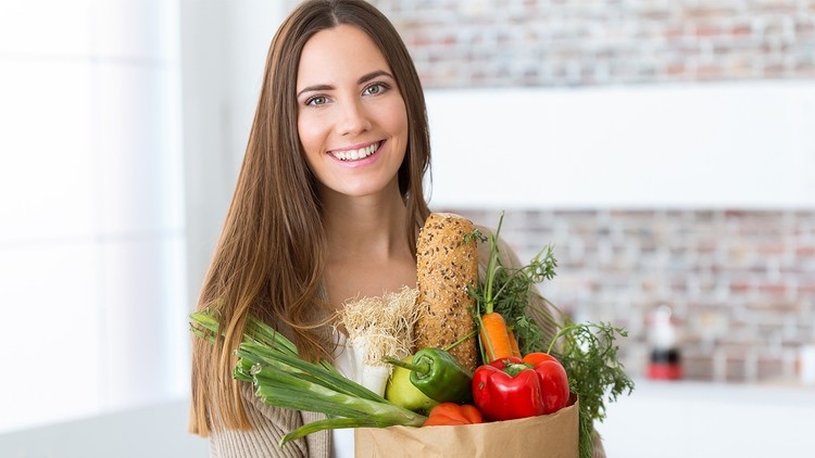 Smiling woman carrying a bag of fresh produce