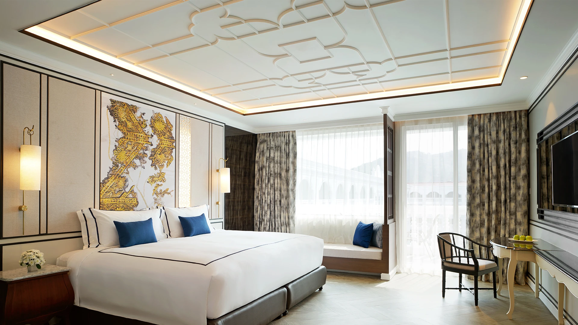 An interior of one of Mövenpick Myth Hotel Patong Phuket's rooms with white walls, a large bed and patterned curtains, part of one of the best family friendly resorts in the world - Luxury Escapes