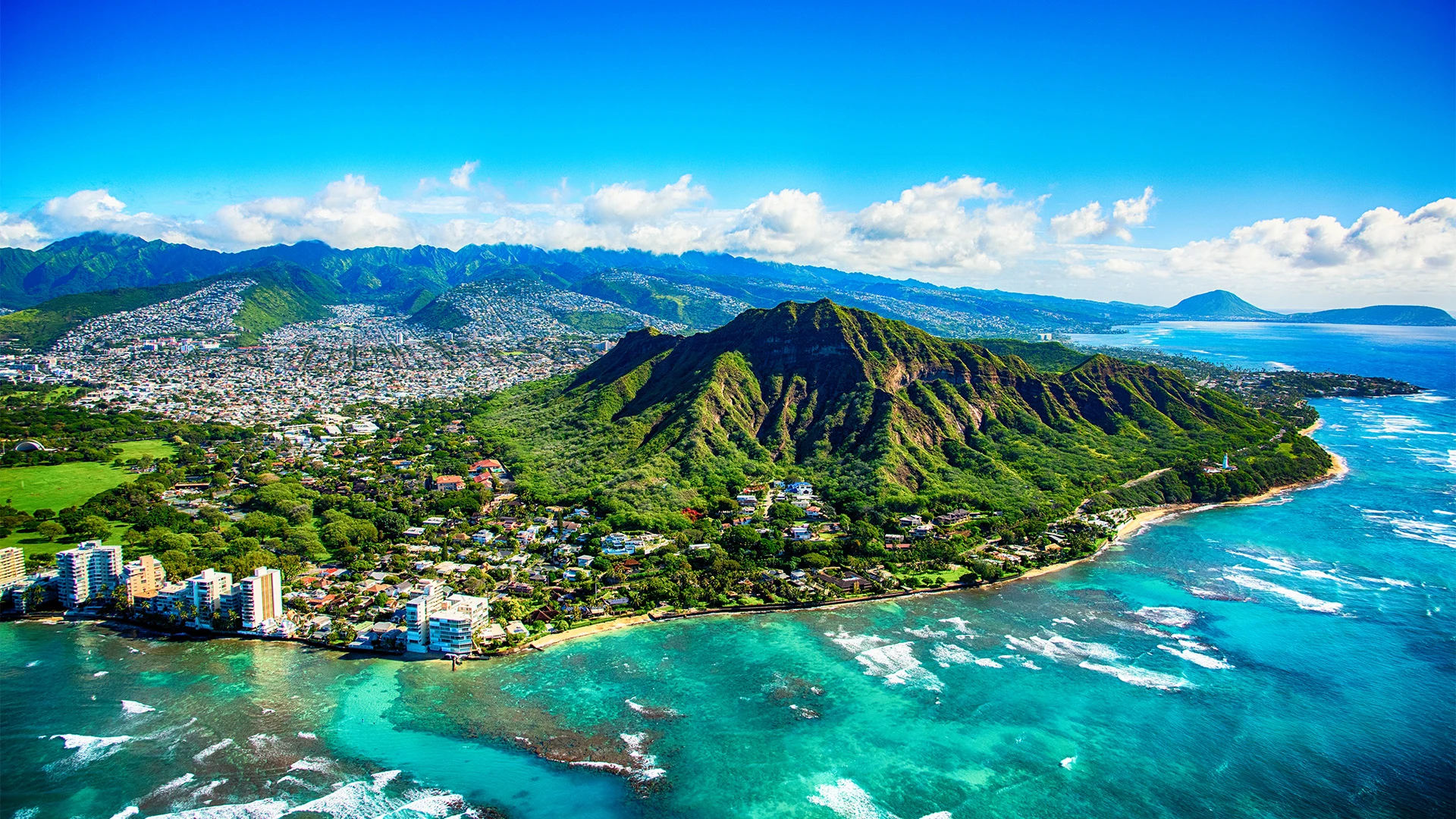 An aerial shot of Waikiki's mountains and Outrigger Waikiki Beachcomber Hotel which is one of the best family friendly resorts in the world - Luxury Escapes